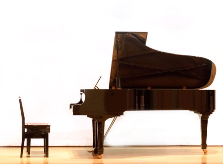 A piano and stool in front of a white wall.